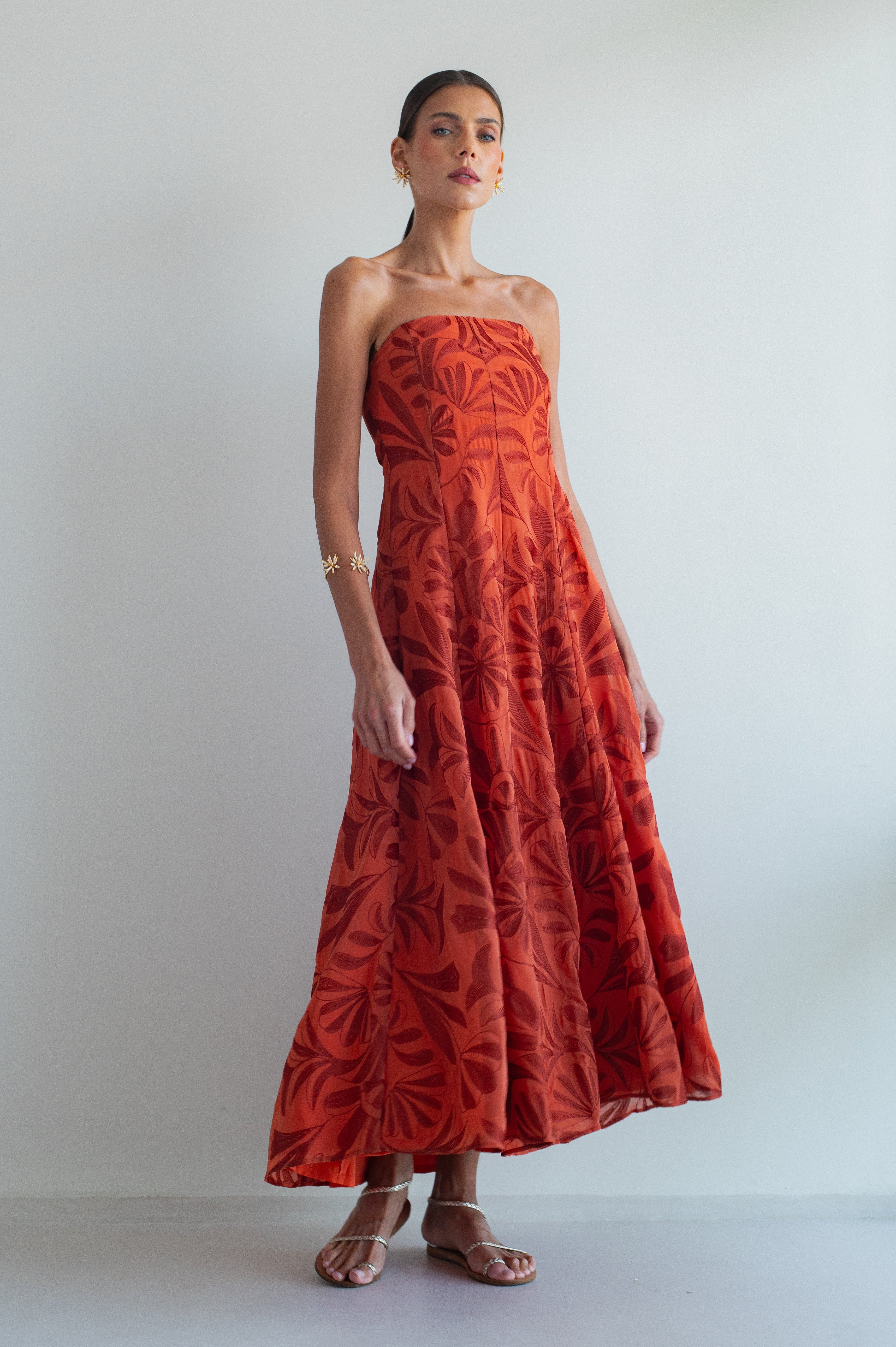 Woman wearing a red strapless dress with a leaf pattern against a white background
